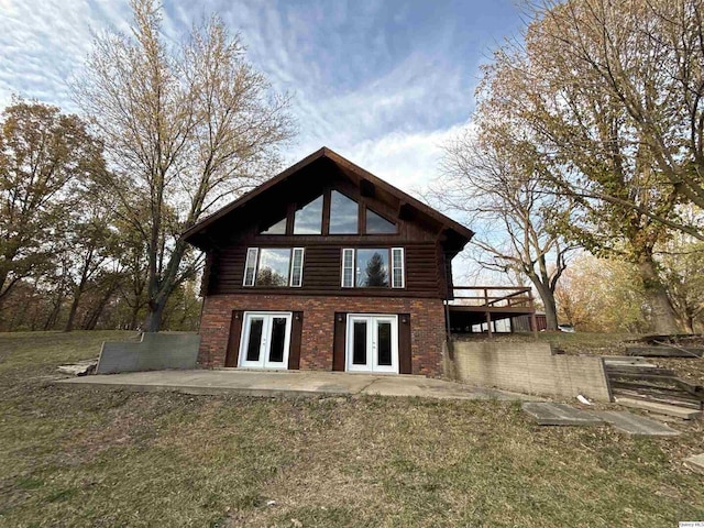 rear view of property featuring a lawn, a patio area, and french doors