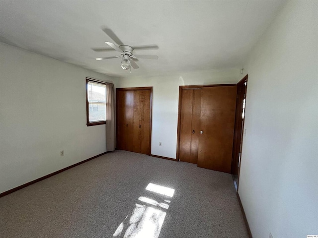 unfurnished bedroom featuring multiple closets, light colored carpet, and ceiling fan