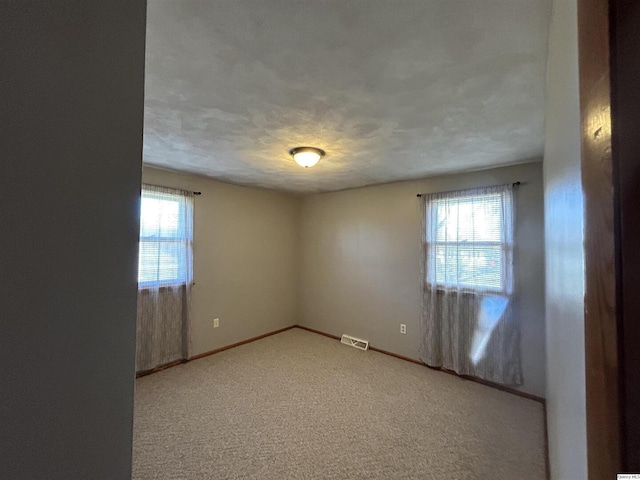 spare room with light carpet and a textured ceiling