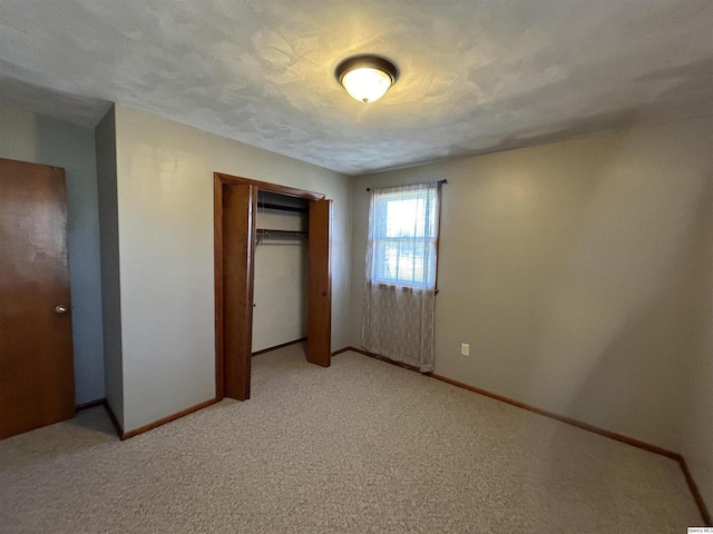 unfurnished bedroom featuring a closet, light carpet, and a textured ceiling