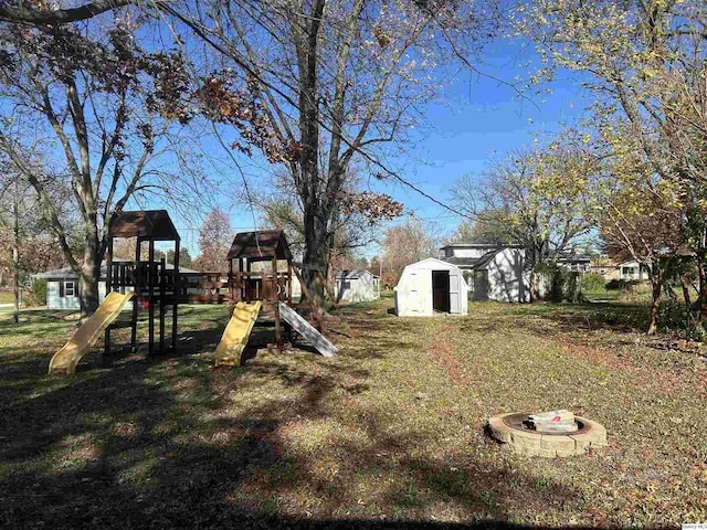 view of yard with an outdoor fire pit, a playground, and a storage unit