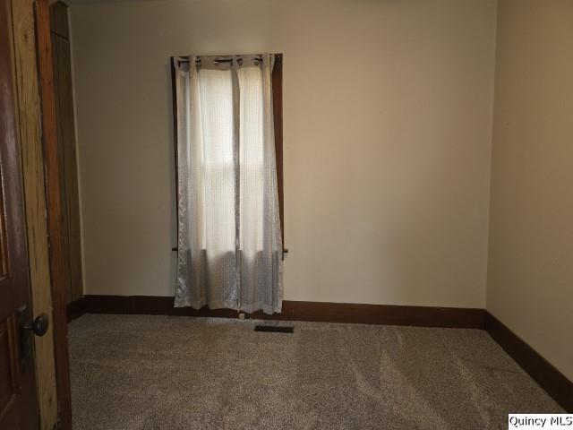 unfurnished room with dark colored carpet and plenty of natural light