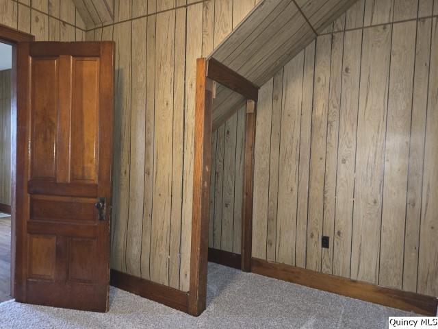 bonus room featuring lofted ceiling, carpet flooring, and wooden walls