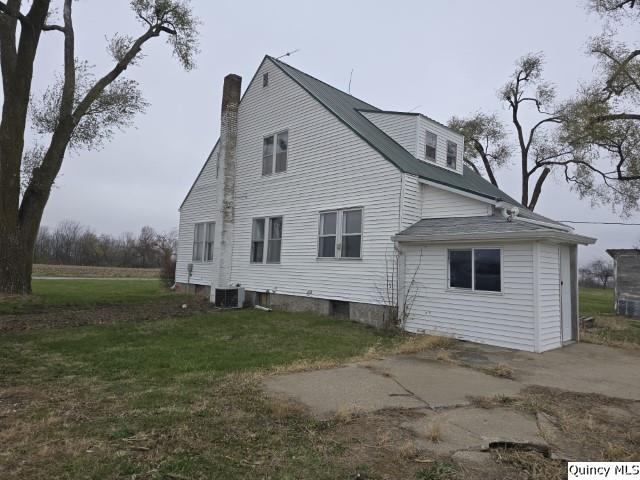 rear view of house with cooling unit and a lawn