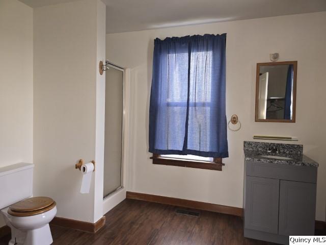 bathroom featuring vanity, toilet, hardwood / wood-style floors, and a shower with shower door