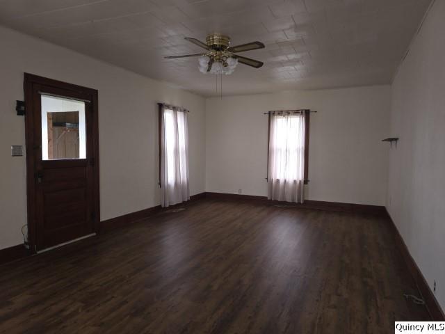 empty room with dark wood-type flooring and ceiling fan