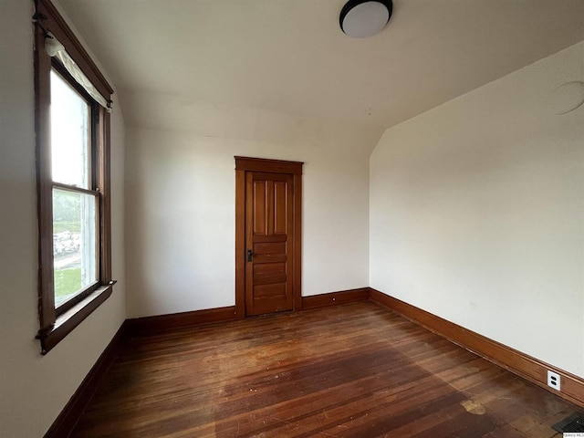 unfurnished room with lofted ceiling, a healthy amount of sunlight, and dark hardwood / wood-style flooring