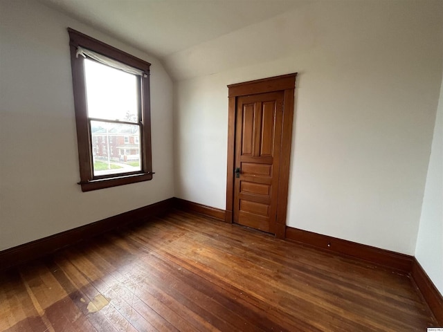 unfurnished room featuring lofted ceiling and dark wood-type flooring