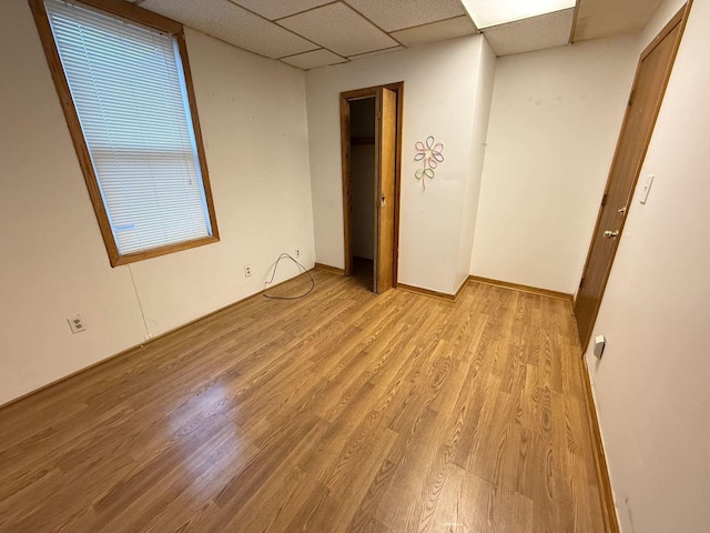 unfurnished room with a paneled ceiling and light wood-type flooring