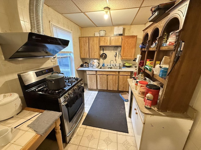 kitchen featuring light tile patterned floors, a paneled ceiling, stainless steel range with gas cooktop, and sink