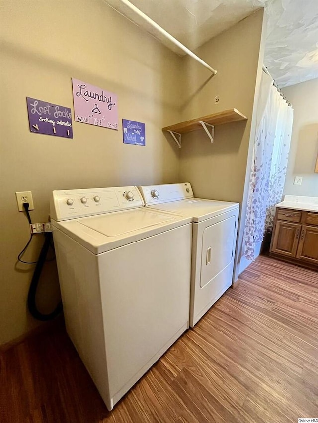 clothes washing area with independent washer and dryer and light hardwood / wood-style floors