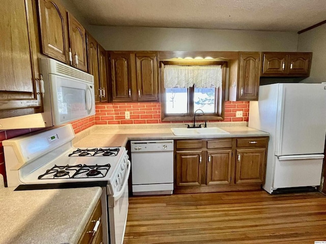 kitchen with sink, white appliances, dark wood-type flooring, tasteful backsplash, and a textured ceiling