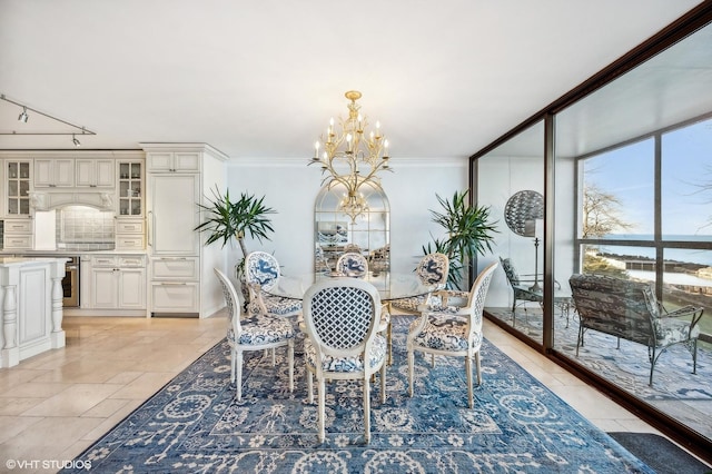 dining room featuring a water view, an inviting chandelier, track lighting, ornamental molding, and expansive windows