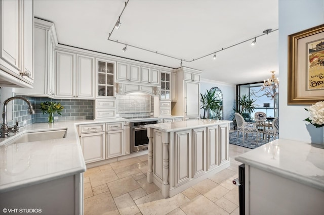 kitchen featuring sink, stainless steel oven, a center island, light stone countertops, and decorative backsplash