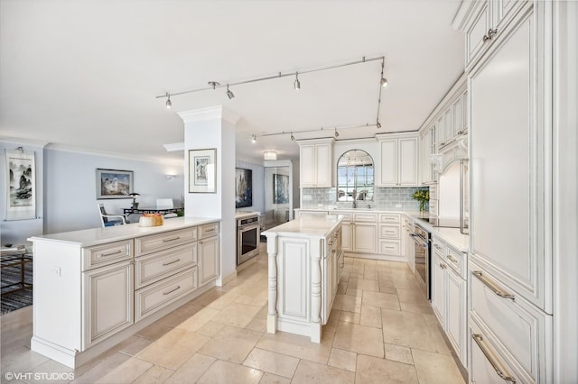 kitchen featuring crown molding, a center island, tasteful backsplash, kitchen peninsula, and oven