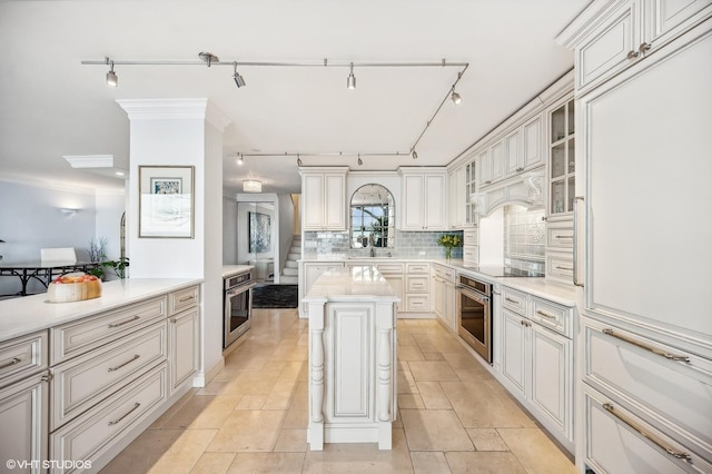 kitchen with black electric cooktop, a center island, oven, and backsplash