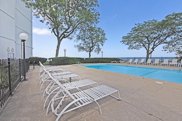 view of swimming pool with a water view and a patio area