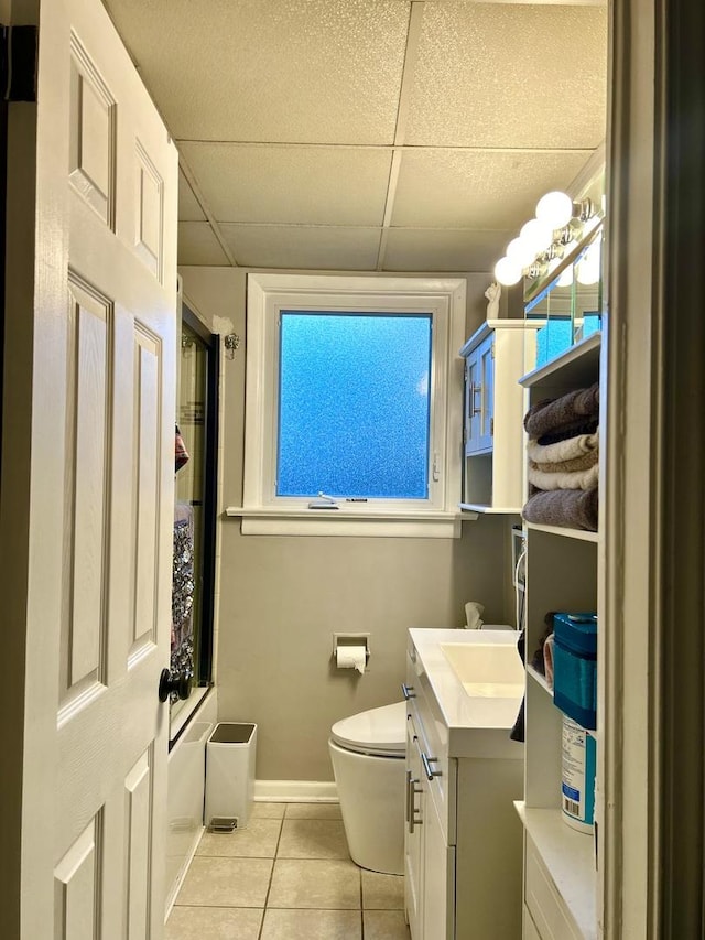 bathroom with tile patterned floors, a drop ceiling, toilet, and vanity