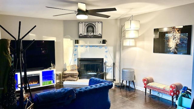 living room featuring hardwood / wood-style floors, ceiling fan, and a tile fireplace