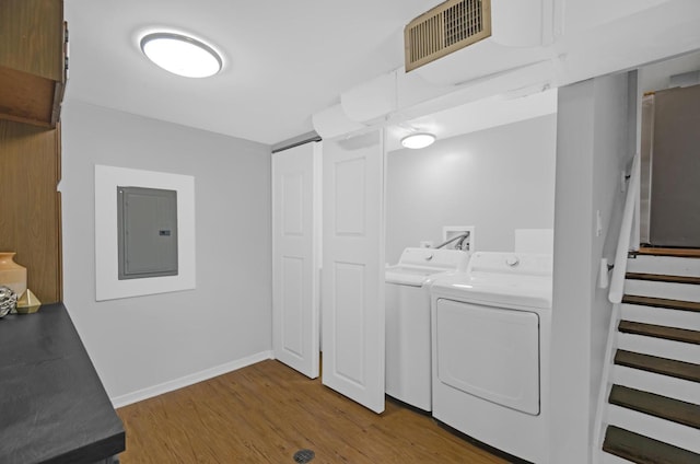 laundry area with wood-type flooring, washing machine and dryer, and electric panel