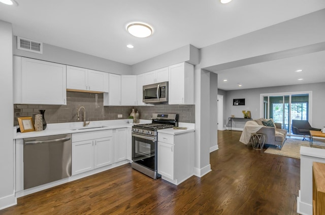 kitchen with dark wood-type flooring, sink, tasteful backsplash, white cabinetry, and stainless steel appliances