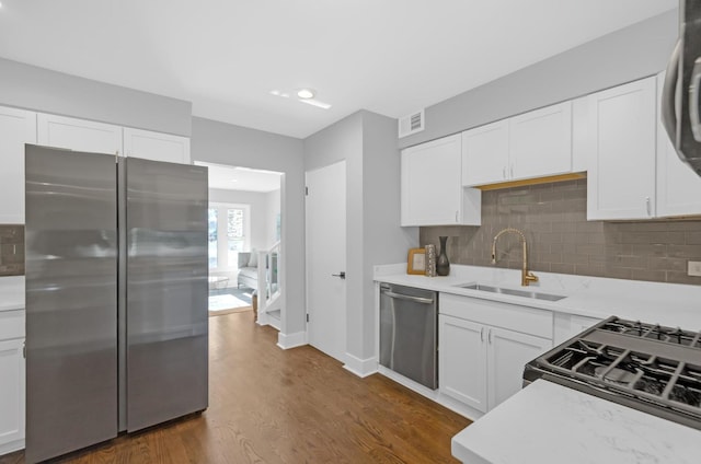 kitchen with appliances with stainless steel finishes, white cabinetry, dark wood-type flooring, and sink