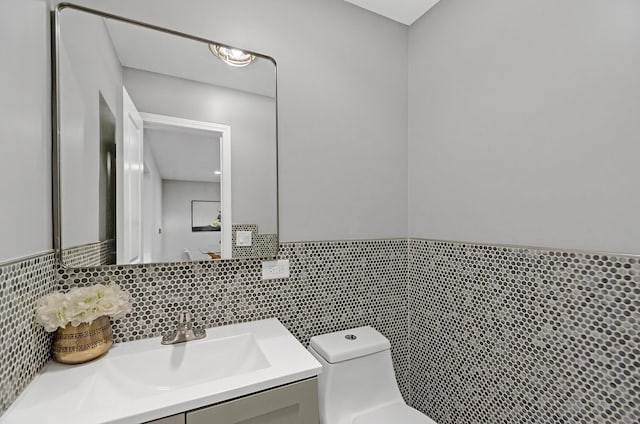 bathroom with vanity, toilet, and tile walls