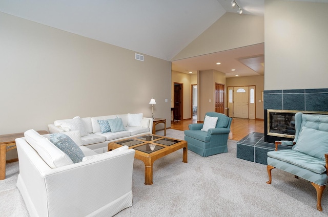 living room with a tiled fireplace and high vaulted ceiling