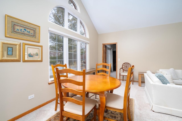 dining room with carpet and high vaulted ceiling