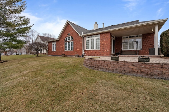 rear view of property featuring a yard, a patio area, and an outdoor fire pit