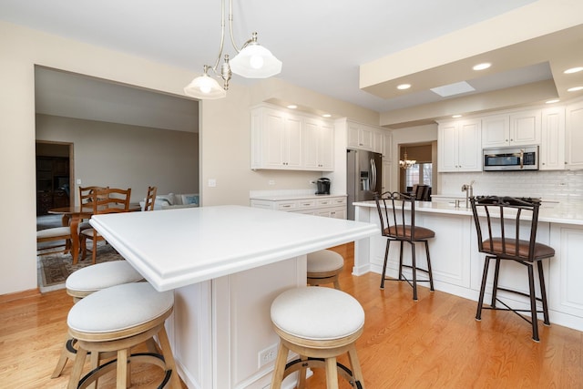 kitchen featuring pendant lighting, a breakfast bar area, white cabinets, and light wood-type flooring