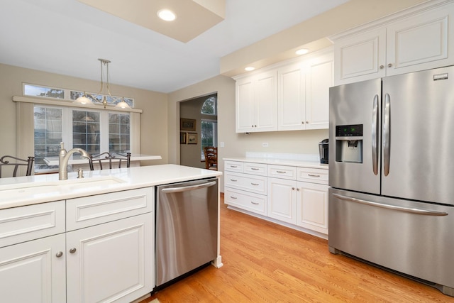 kitchen with pendant lighting, stainless steel appliances, sink, and white cabinets