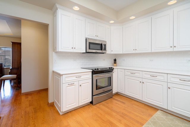 kitchen featuring backsplash, stainless steel appliances, light hardwood / wood-style floors, and white cabinets