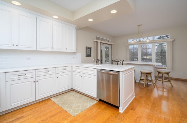 kitchen featuring white cabinetry, stainless steel dishwasher, kitchen peninsula, and sink