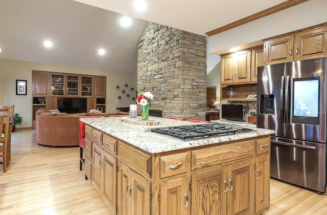 kitchen with a center island, light stone counters, decorative backsplash, light wood-style flooring, and appliances with stainless steel finishes