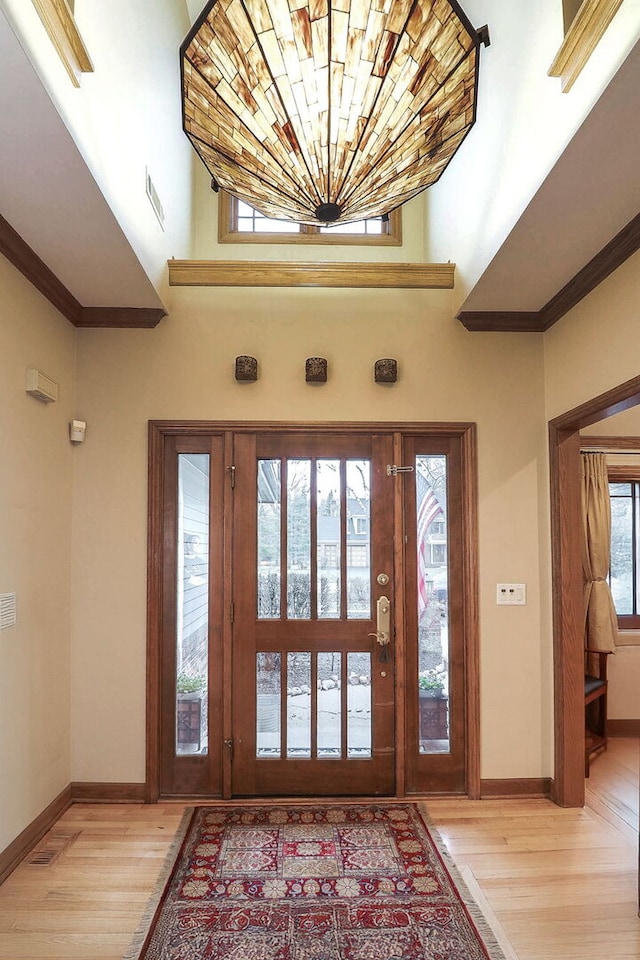 foyer entrance featuring baseboards, light wood-type flooring, and ornamental molding