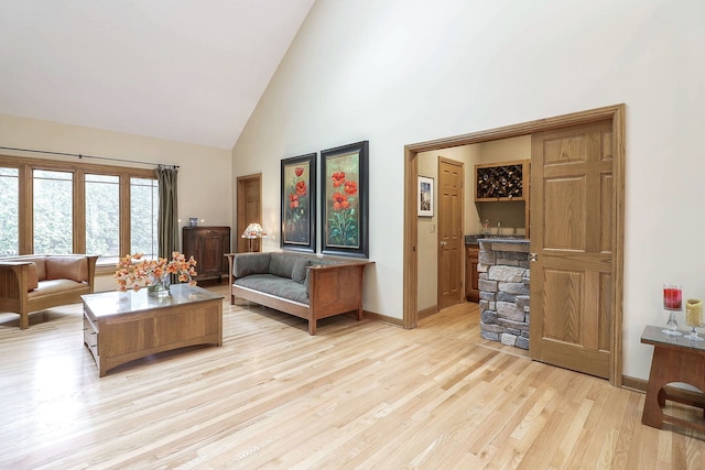 living area with light wood finished floors, high vaulted ceiling, and baseboards