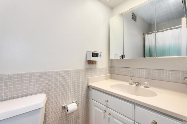 bathroom featuring vanity, toilet, and tile walls