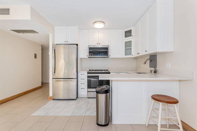 kitchen featuring sink, a breakfast bar area, white cabinetry, kitchen peninsula, and stainless steel appliances