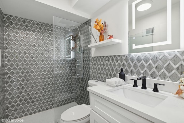 bathroom with vanity, toilet, tile walls, and a tile shower