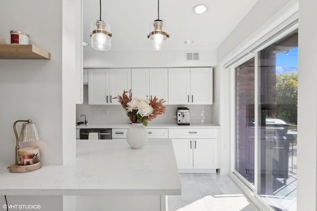 kitchen featuring white cabinets, pendant lighting, backsplash, and light stone counters