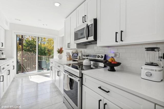 kitchen featuring light tile patterned flooring, white cabinetry, backsplash, and appliances with stainless steel finishes