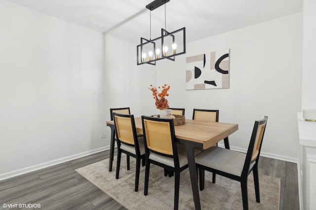 dining room with dark hardwood / wood-style floors and an inviting chandelier