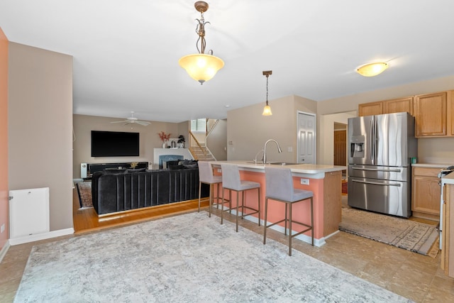 kitchen with ceiling fan, sink, stainless steel fridge, decorative light fixtures, and a breakfast bar