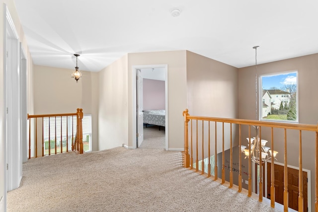 hallway with carpet flooring and an inviting chandelier