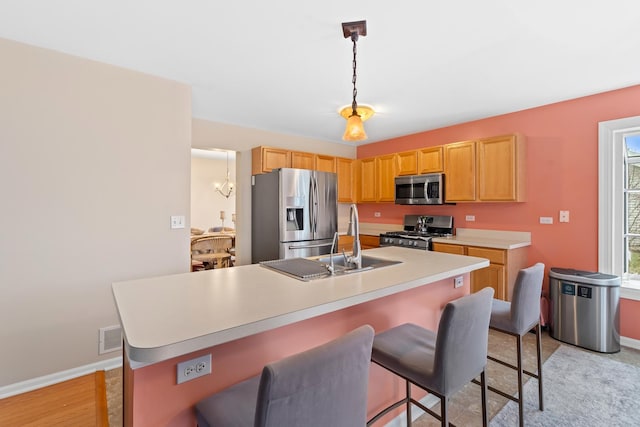 kitchen featuring a breakfast bar area, a kitchen island with sink, light hardwood / wood-style flooring, and appliances with stainless steel finishes