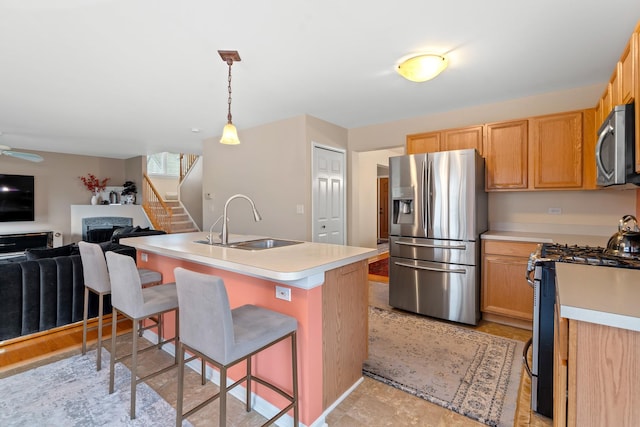 kitchen with sink, hanging light fixtures, a breakfast bar, a center island with sink, and appliances with stainless steel finishes