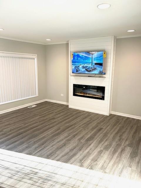 unfurnished living room featuring a large fireplace, dark hardwood / wood-style floors, and ornamental molding