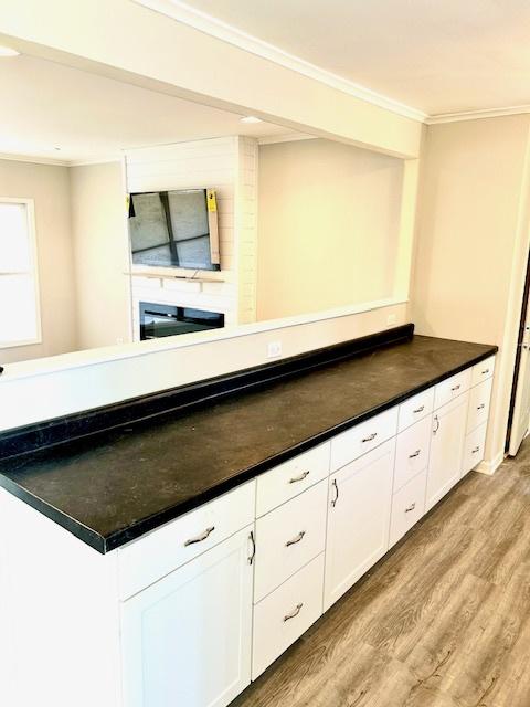 kitchen featuring white cabinetry, light hardwood / wood-style flooring, and ornamental molding