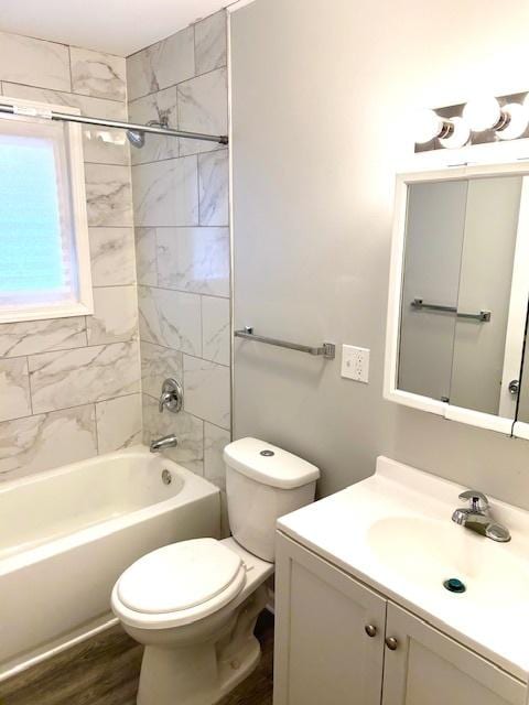 full bathroom featuring hardwood / wood-style floors, vanity, tiled shower / bath combo, and toilet